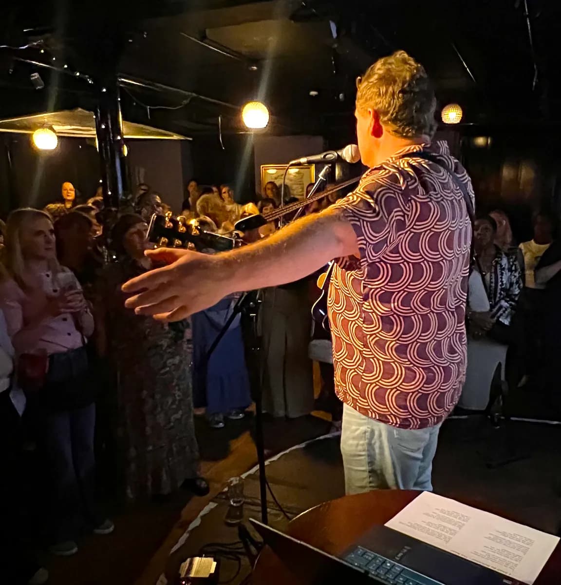 The conductor leading the room, arms wide